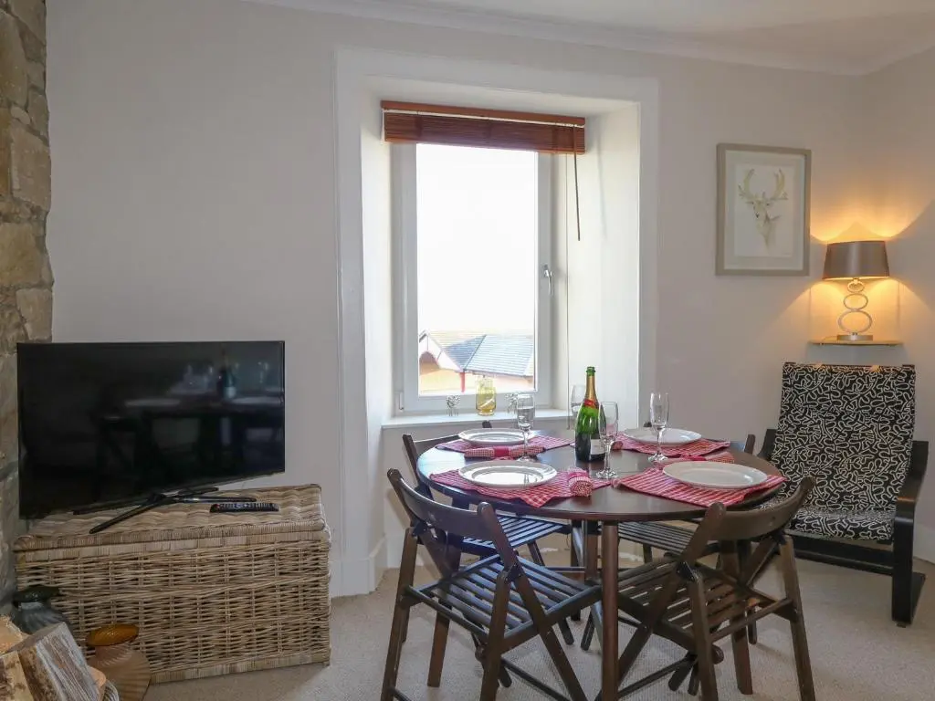 a dining room with a table and chairs and a television at Seascape in Lossiemouth