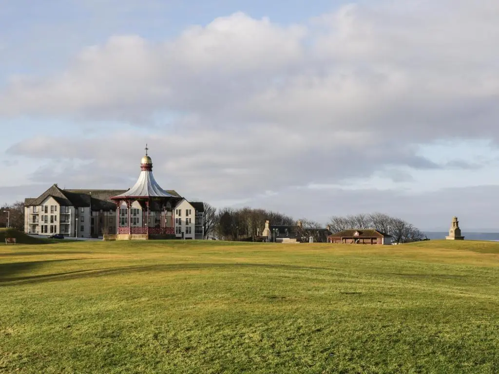 a large grassy field with a large building with a tower at Seaview in Nairn