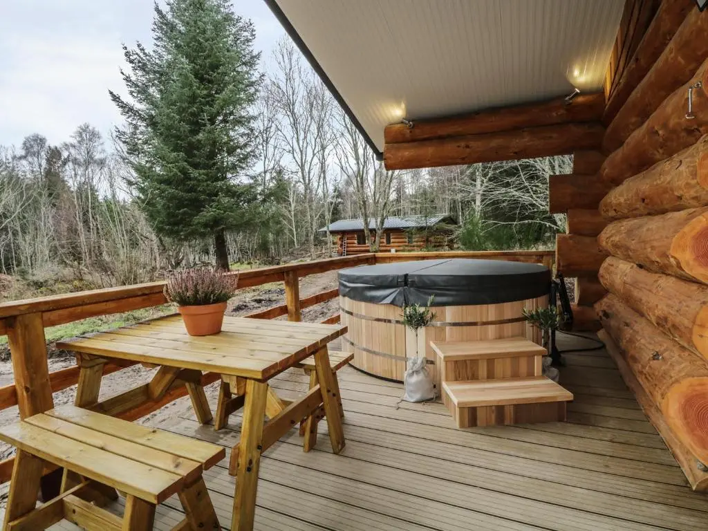 a wooden deck with a picnic table and a hot tub at Moorhen Lodge in Inverness