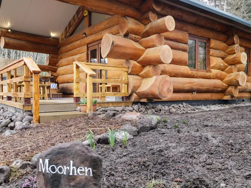 a log cabin with a pile of logs on it at Moorhen Lodge in Inverness