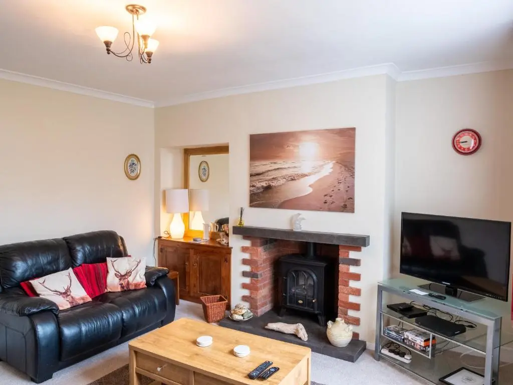 a living room with a black leather couch and a fireplace at BalMara in Hopeman
