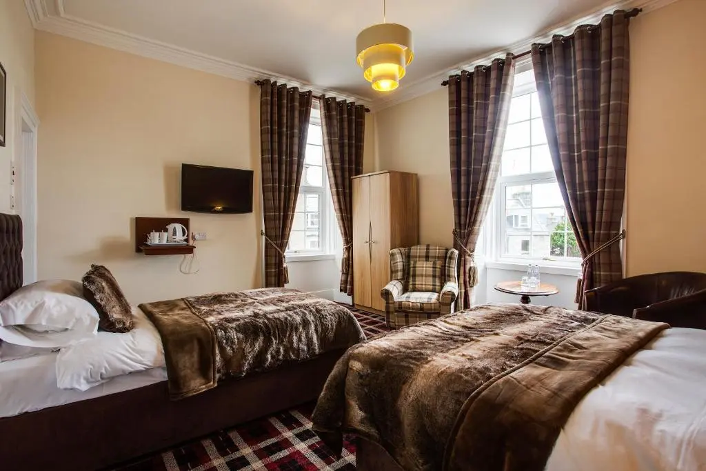 a hotel room with a bed and a chair at Haughton Arms Hotel in Alford