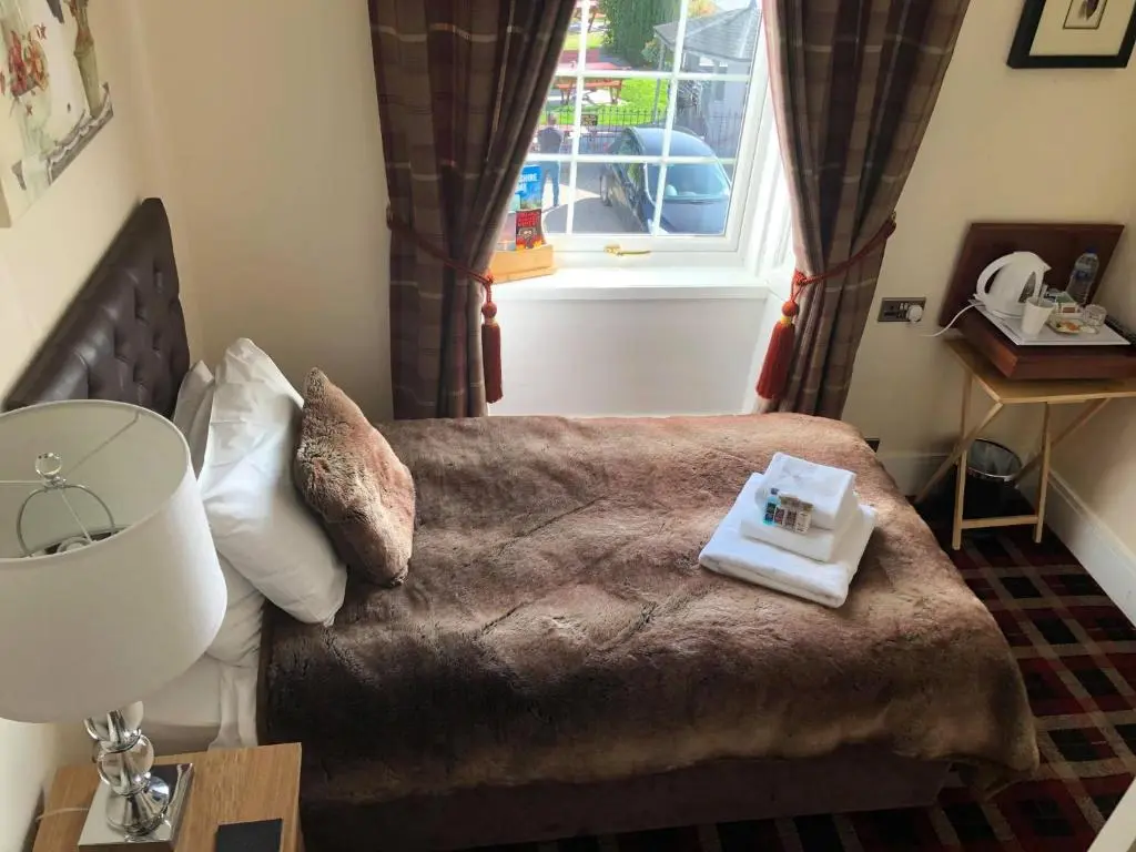 a bedroom with a bed with a book on it at Haughton Arms Hotel in Alford