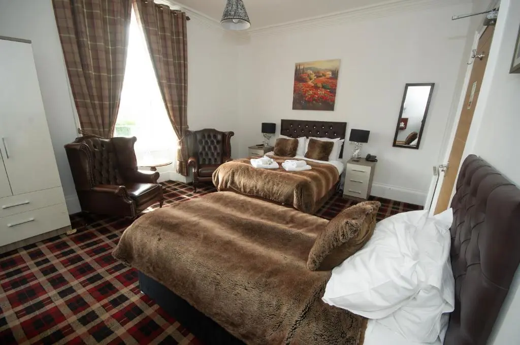 a hotel room with two beds and a couch at Haughton Arms Hotel in Alford