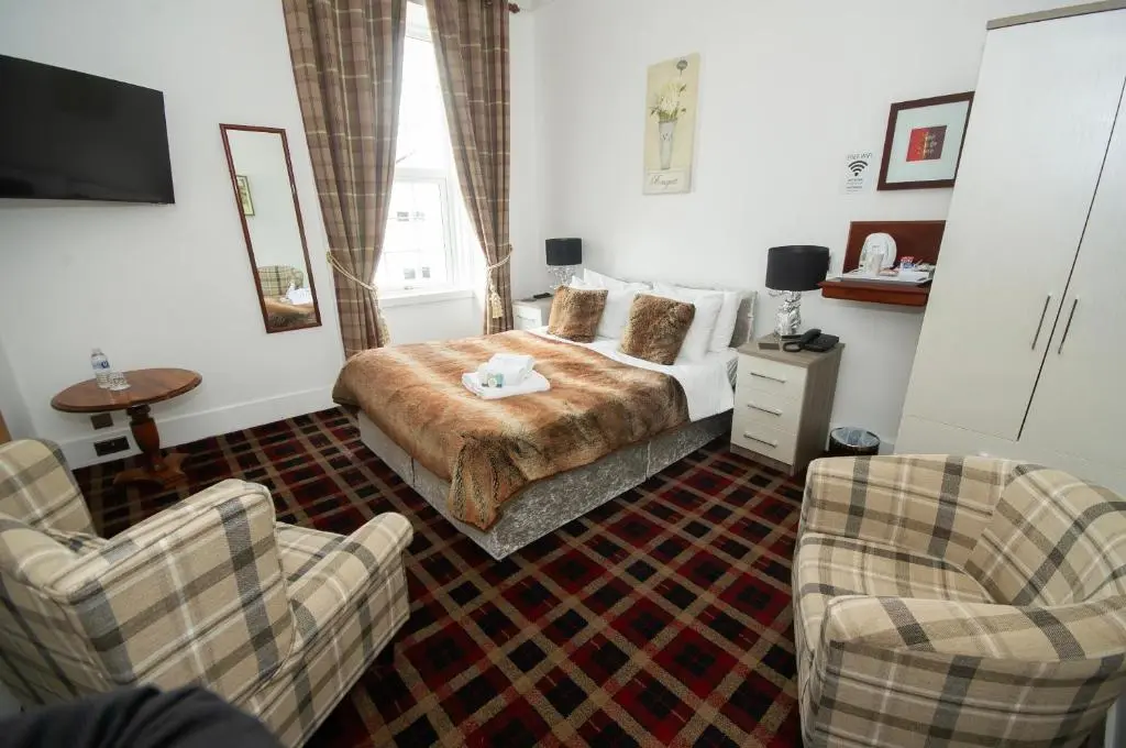 a bedroom with a bed and two chairs at Haughton Arms Hotel in Alford
