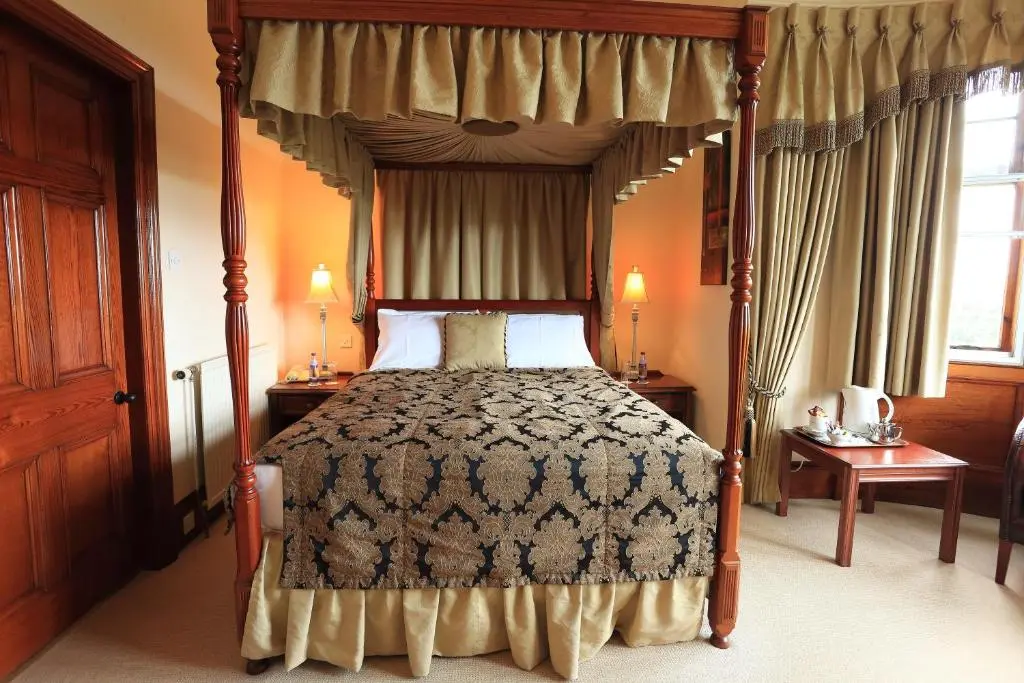 a bedroom with a four poster bed with a canopy at Ramnee Hotel in Forres