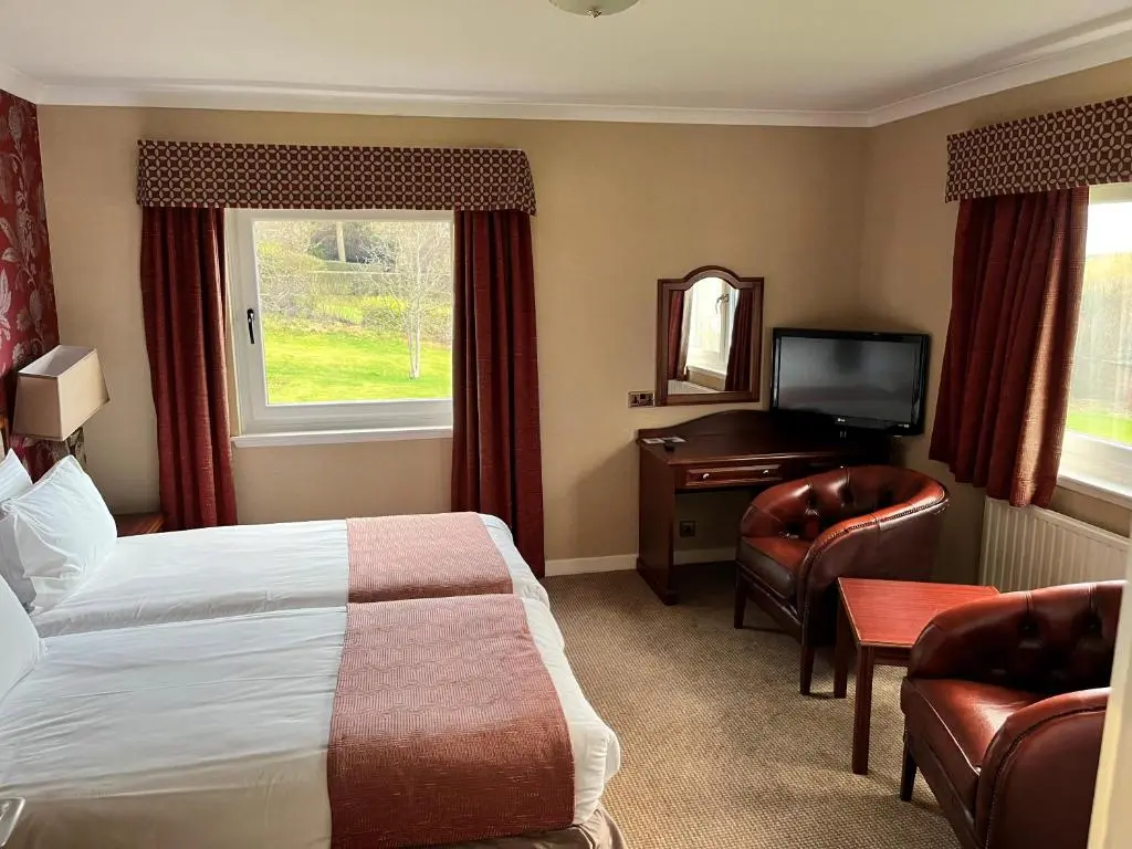 a hotel room with a bed and a television at Ramnee Hotel in Forres