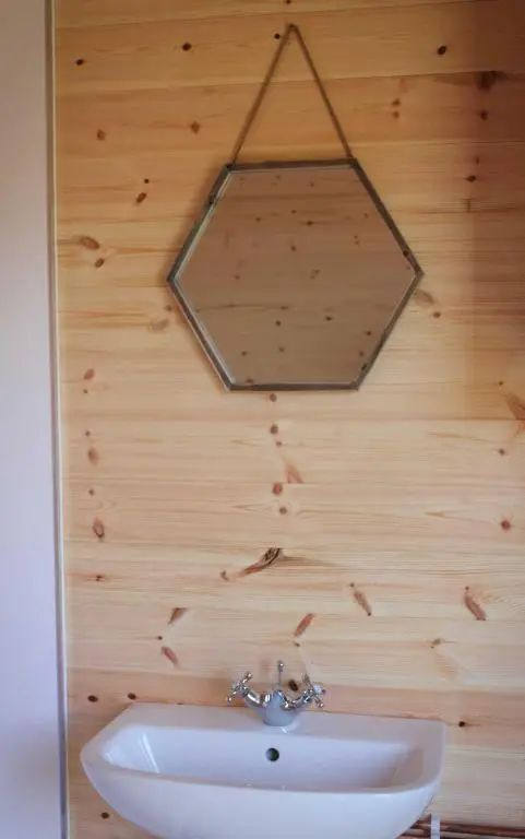a mirror hanging on a wooden wall with a sink at Howe of Torbeg in Ballater