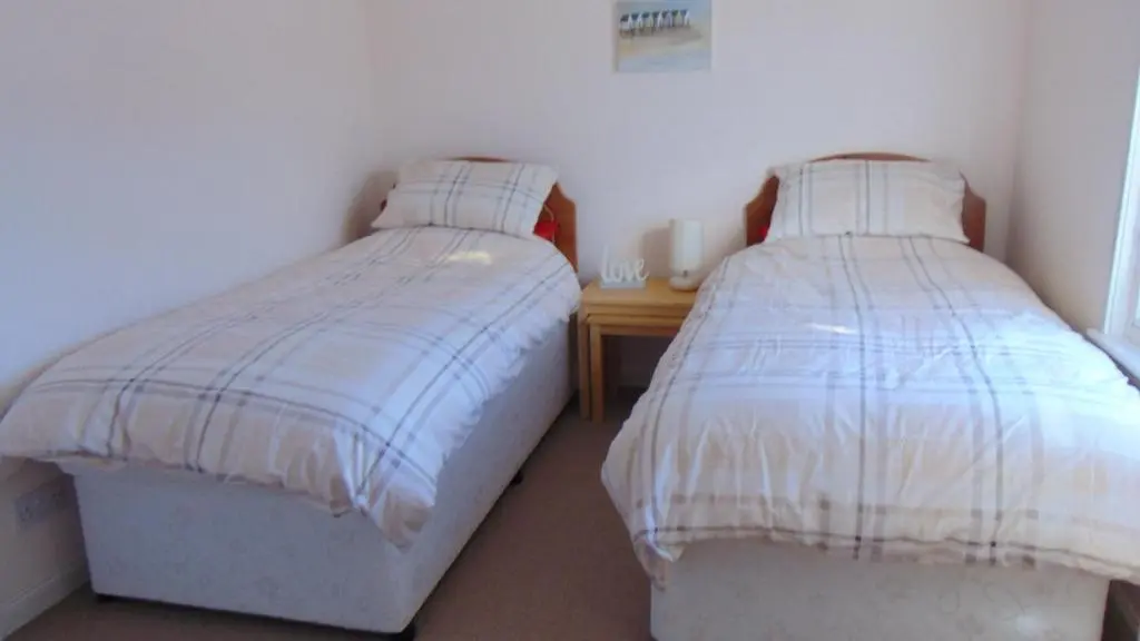 a bedroom with two beds and a wooden table at Montclaire in Ballater