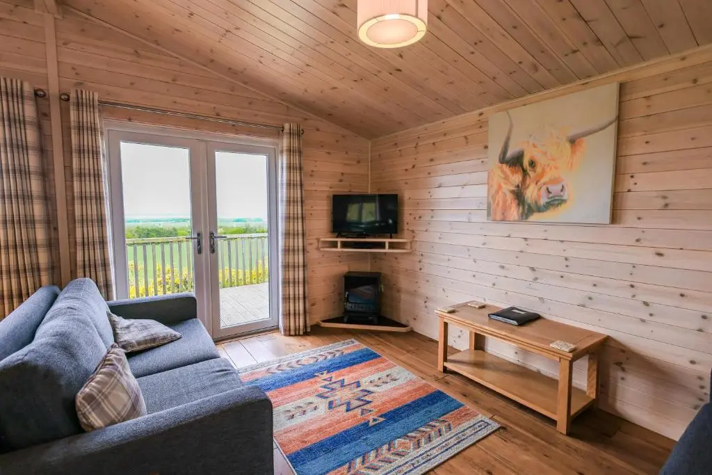 a living room with a couch and a tv at Burgie Woodland Lodges in Forres