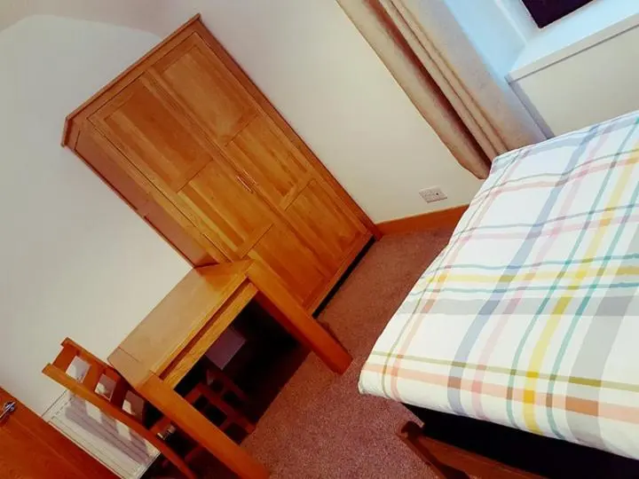 a bedroom with a bed and a wooden table and chair at Yvi's 2-3 Bedroom Town Apartment in Inverurie
