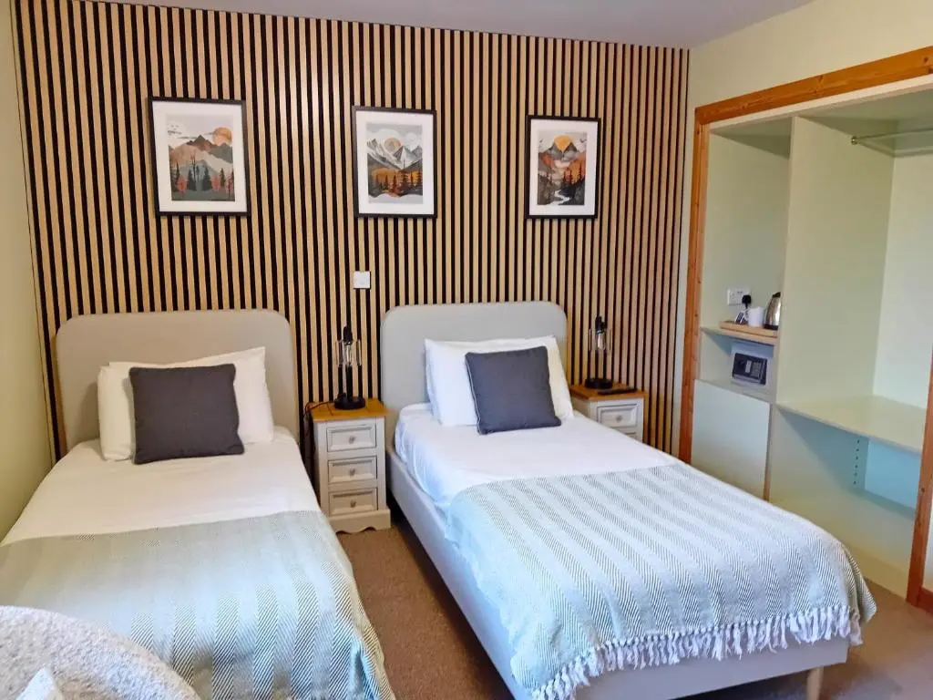 a bedroom with two beds and a striped wall at Deveron Lodge B&B in Turriff