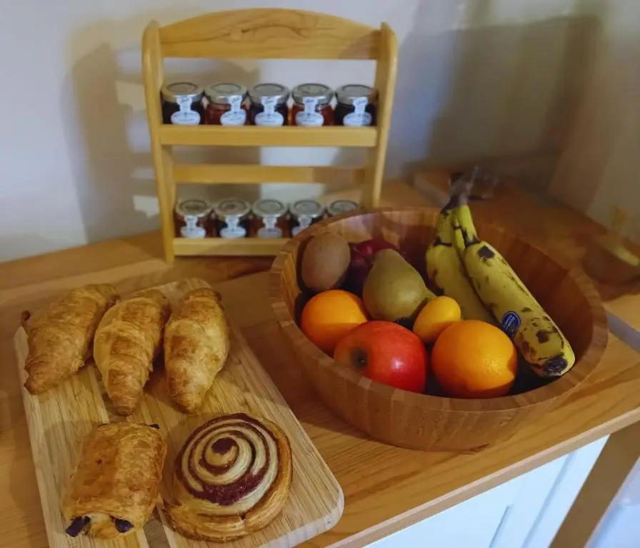 a table with a bowl of fruit and a bowl of bread at Deveron Lodge B&B in Turriff