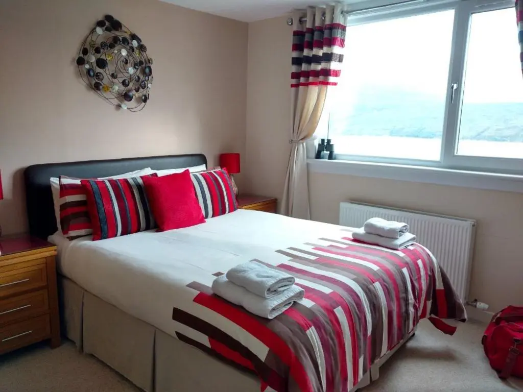 a bedroom with a large bed with towels on it at Ardlair Guest House in Ullapool