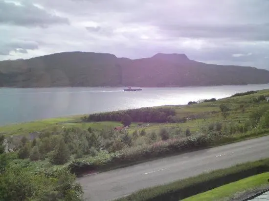a boat in a large body of water with mountains at Ardlair Guest House in Ullapool