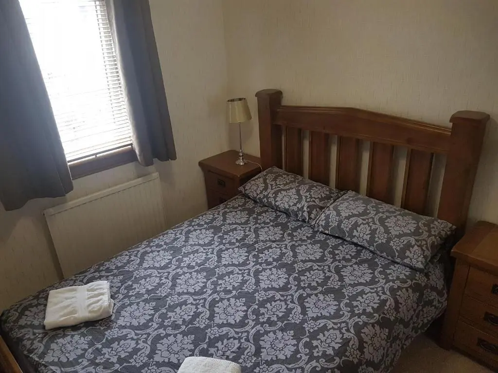 a bed with a blue and white comforter and a window at Jane's Place Free Parking in Inverness