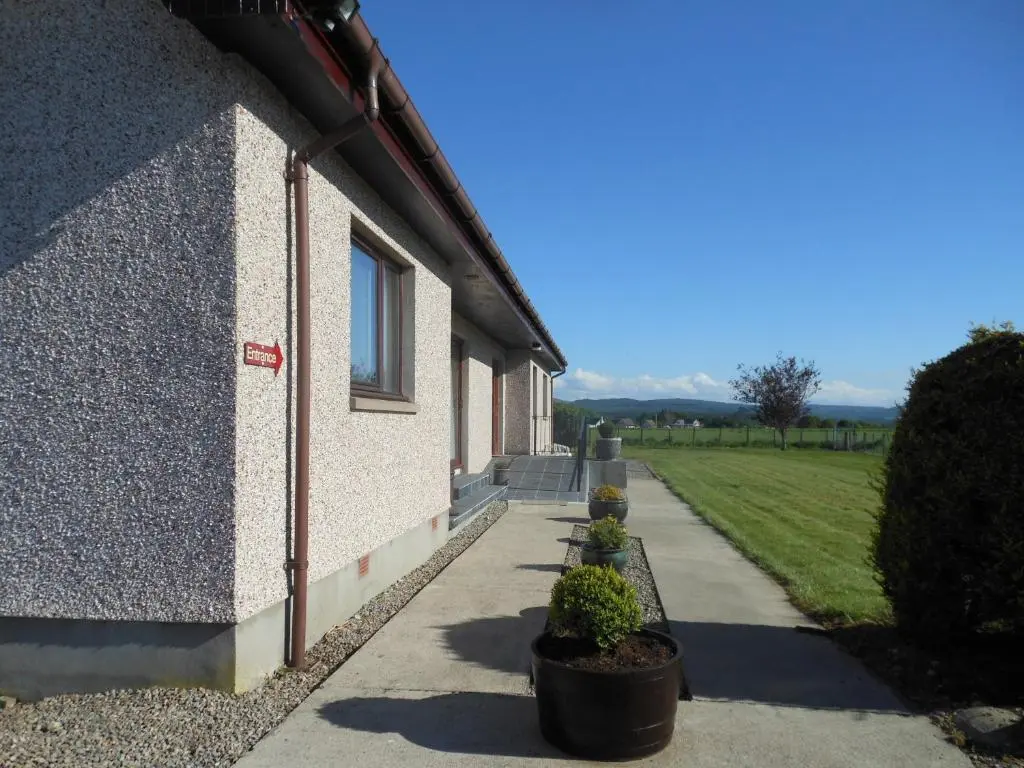 a building with potted plants next to a sidewalk at Hillview Park in Beauly