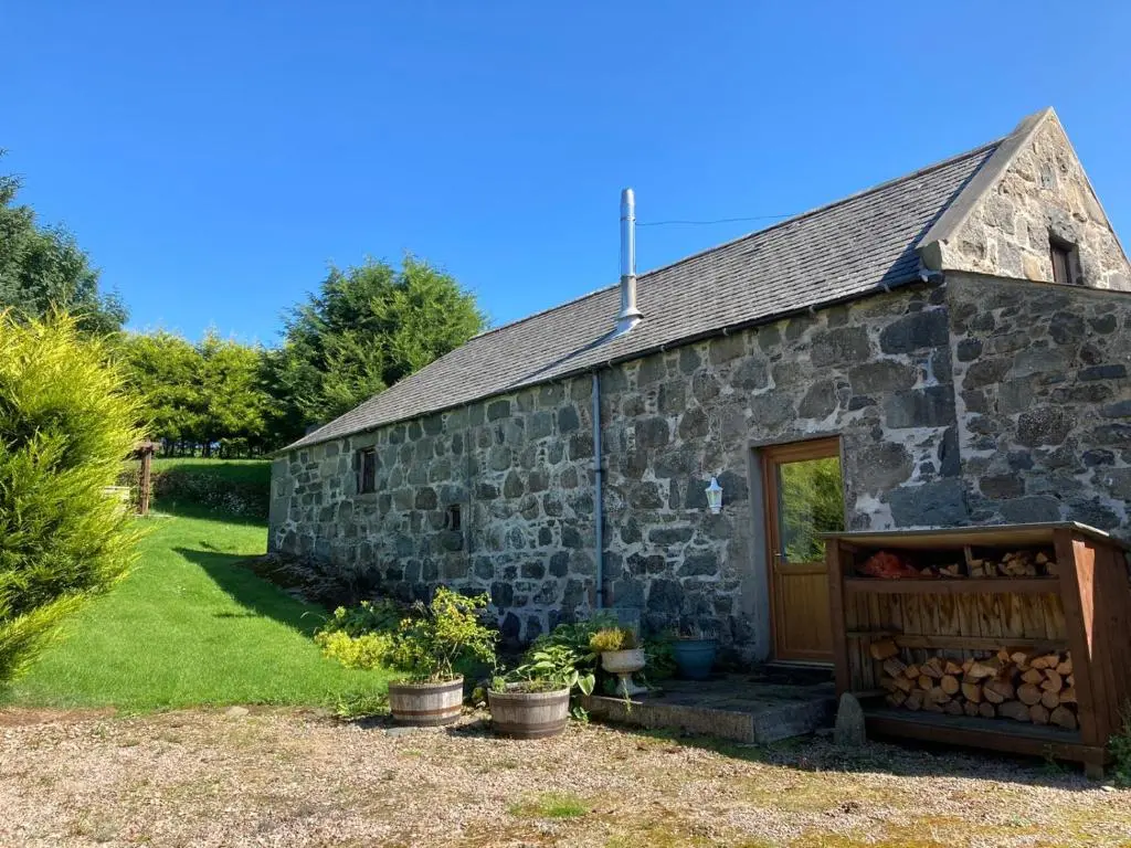 an old stone building with a door and a yard at Woodside Steading in Huntly