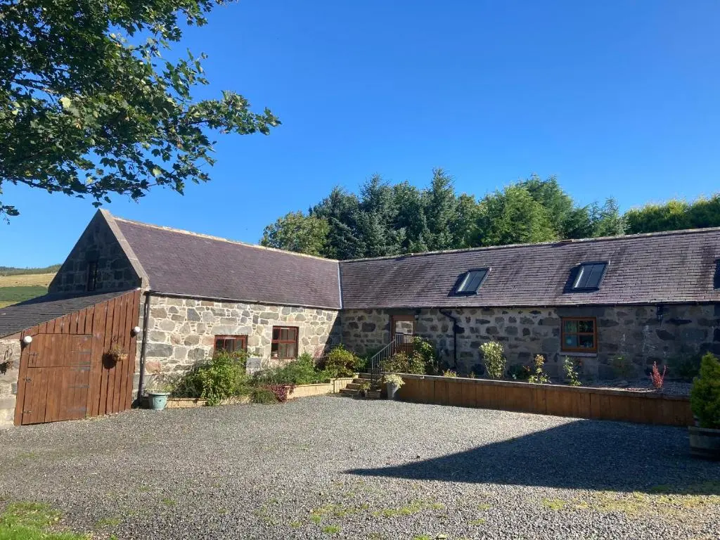a stone building with a barn with a driveway at Woodside Steading in Huntly