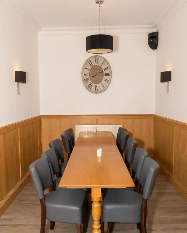 a conference room with a table and chairs and a clock at Station Hotel in Ellon