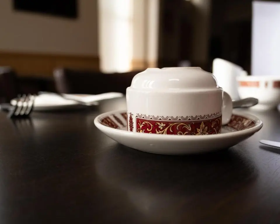 a cup of coffee on a plate on a table at Station Hotel in Ellon