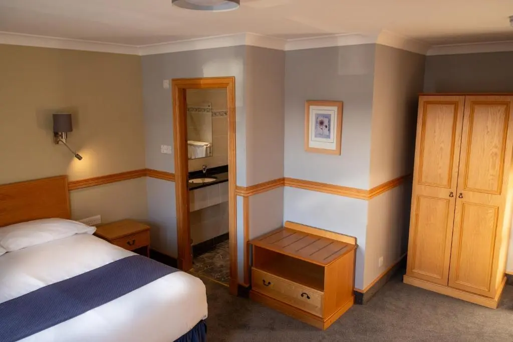 a small bedroom with a bed and a mirror at Station Hotel in Ellon