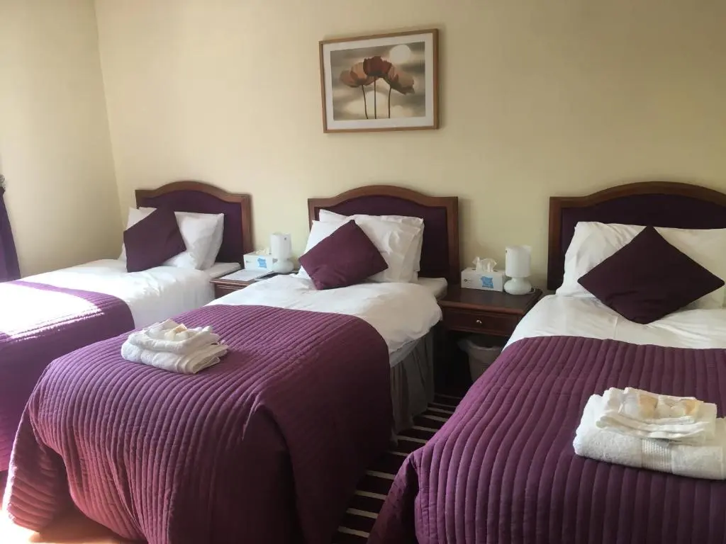 a hotel room with two beds with purple blankets at Gordon House in Tomintoul