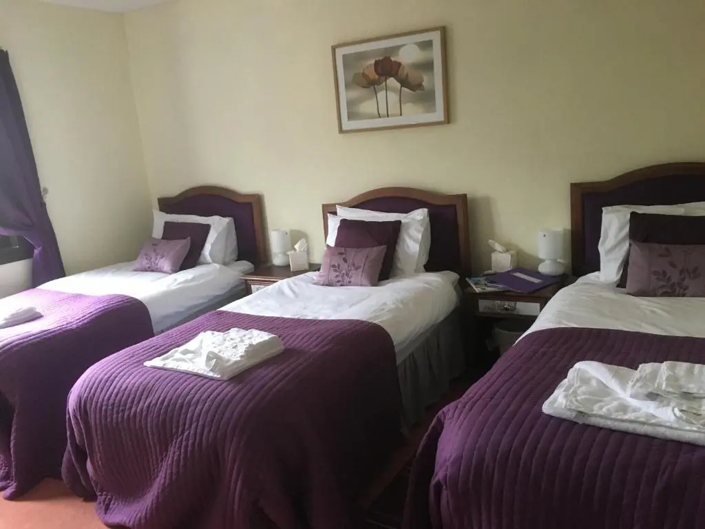 a hotel room with two beds with purple sheets at Gordon House in Tomintoul