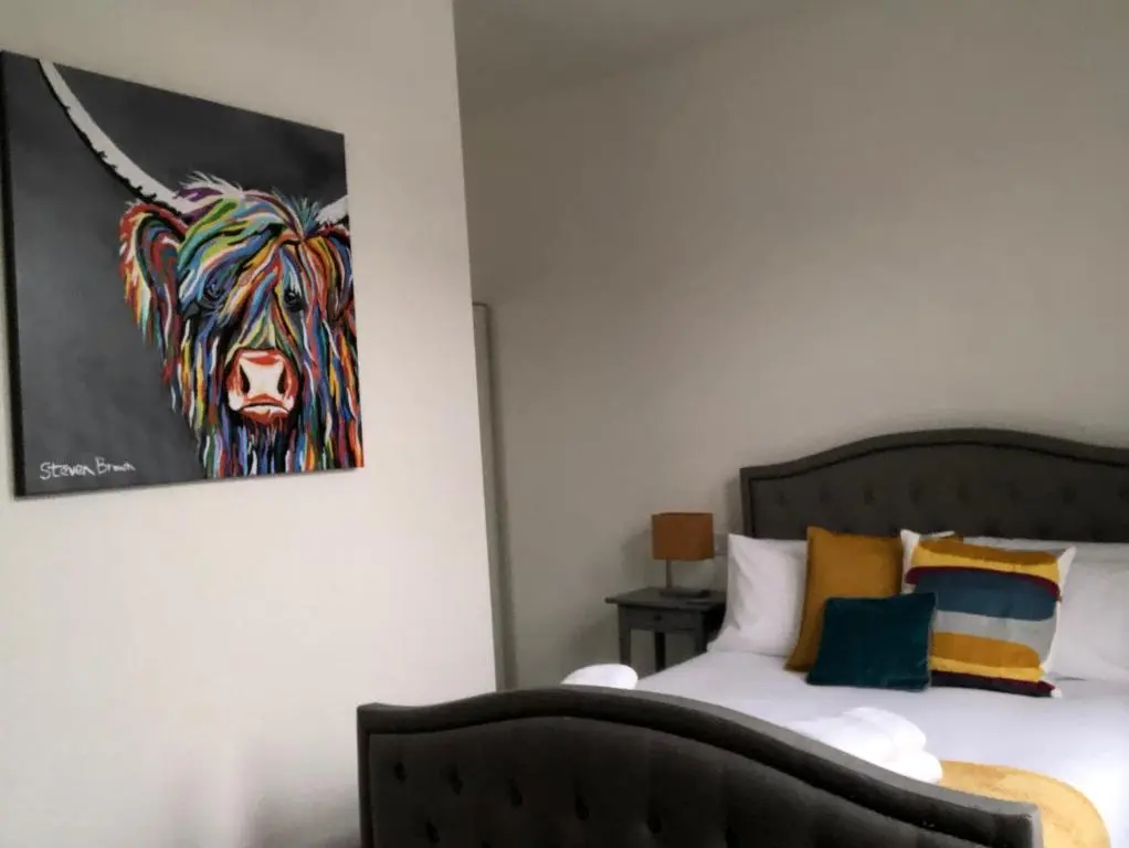 a bedroom with a painting of a cow on the wall at Dryburgh Apartment No3 in Inverness