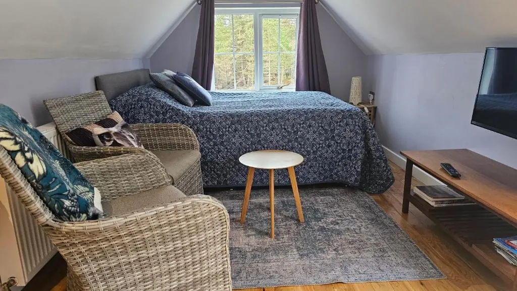 a bedroom with a bed and a chair and a table at The Den , Sengera in Inverness