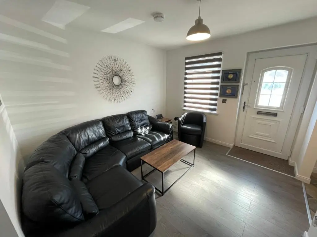 a living room with a black leather couch and a table at Foxglove Apartment in Inverness