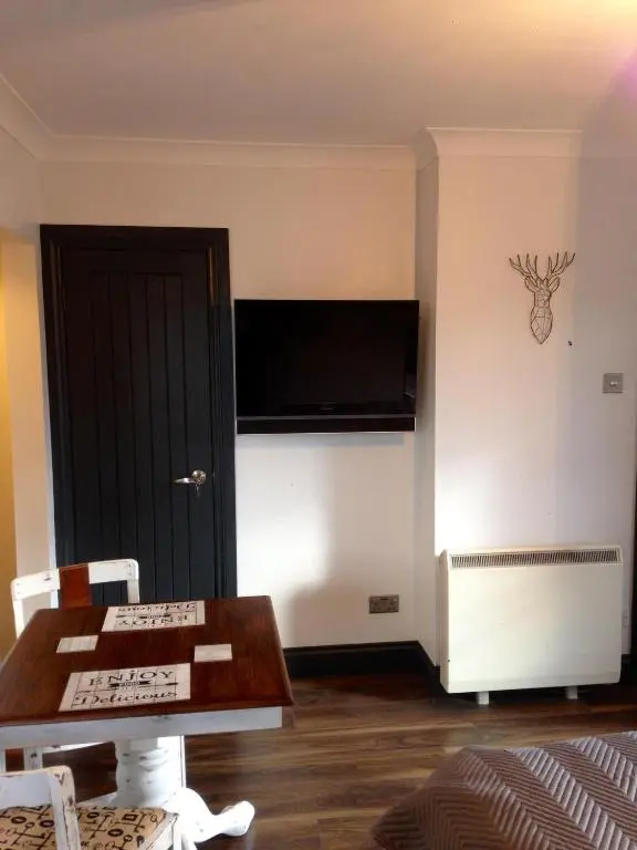 a living room with a table and a tv on the wall at Caledonian Canal Studio in Inverness