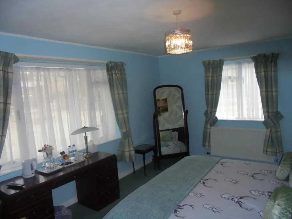 a bedroom with a bed and a dresser and a mirror at Avondale House in Kingussie