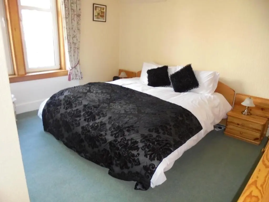 a bedroom with a bed with a black and white comforter at Avondale House in Kingussie