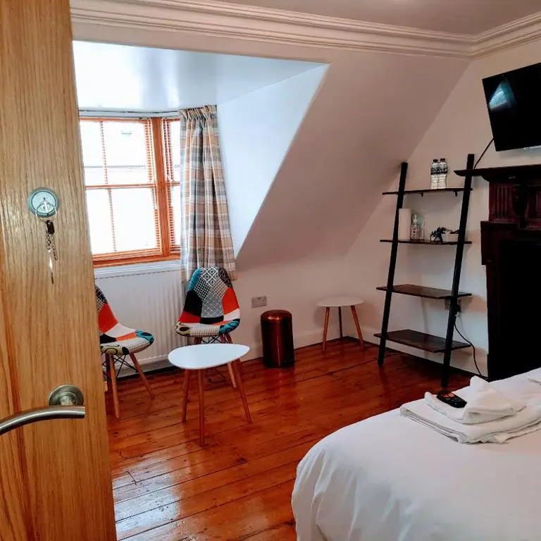 a bedroom with a bed and chairs and a window at Ness City Cottage in Inverness