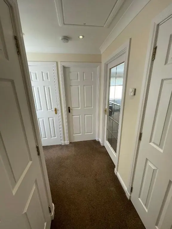 a hallway with white doors and brown carpet at Holm from Home in Inverness