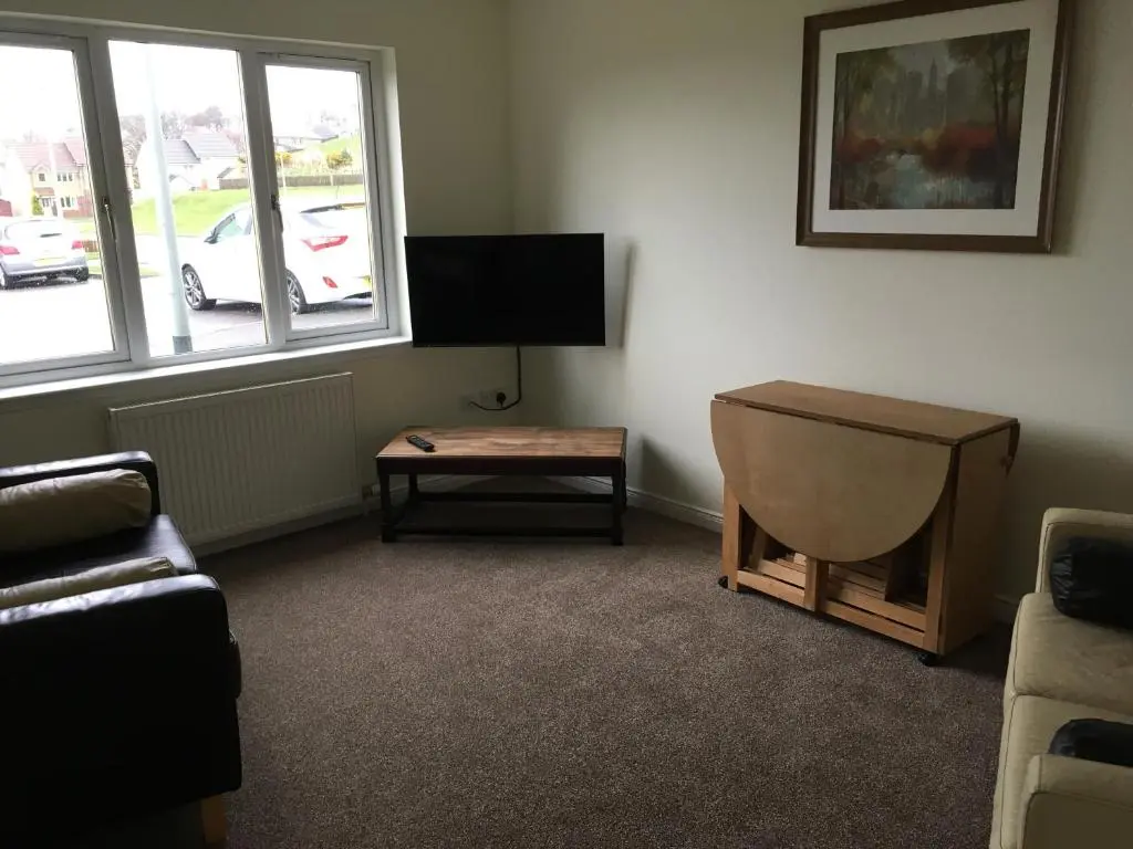 a living room with a couch and a tv and a table at Morning Field Apartment Free Parking in Inverness
