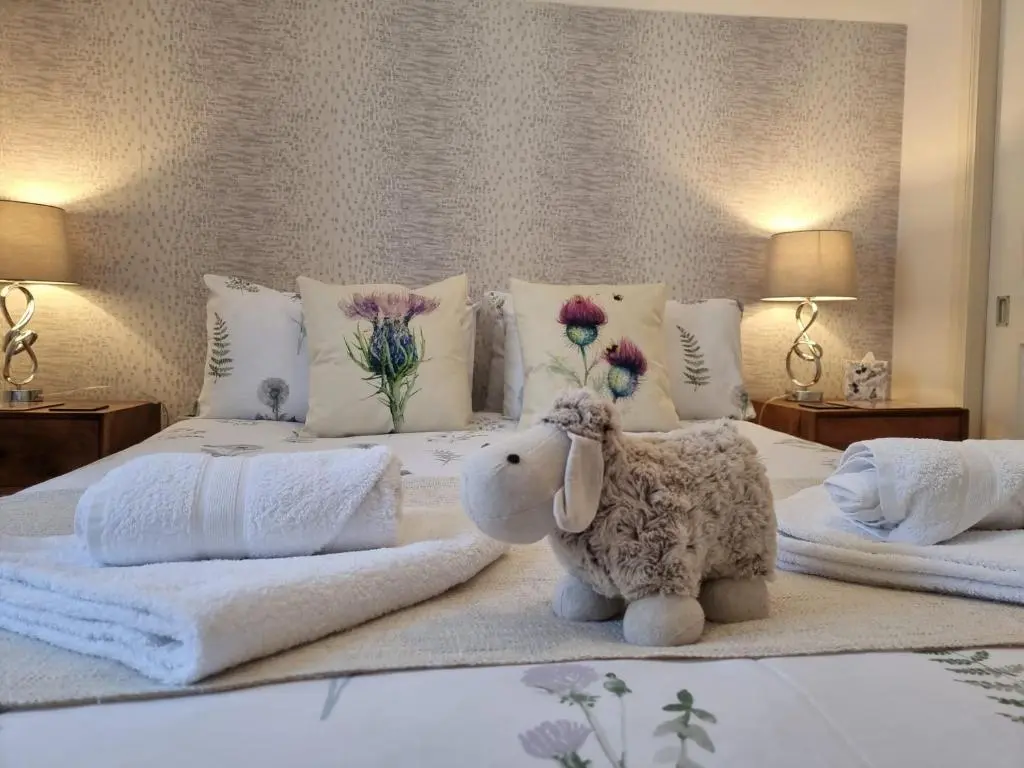 a bedroom with a white bed with flowers on it at Heart of Inverness-city apartment in Inverness
