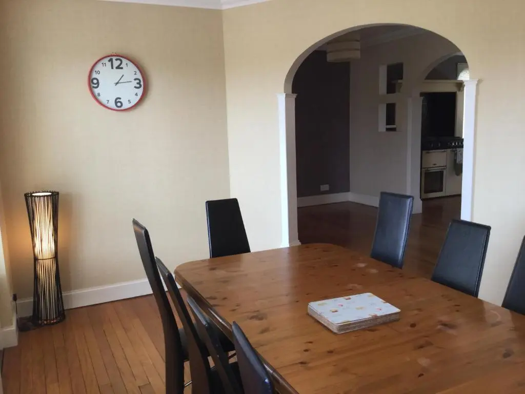 a dining room with a table and a clock on the wall at West Heather House Free Parking in Inverness