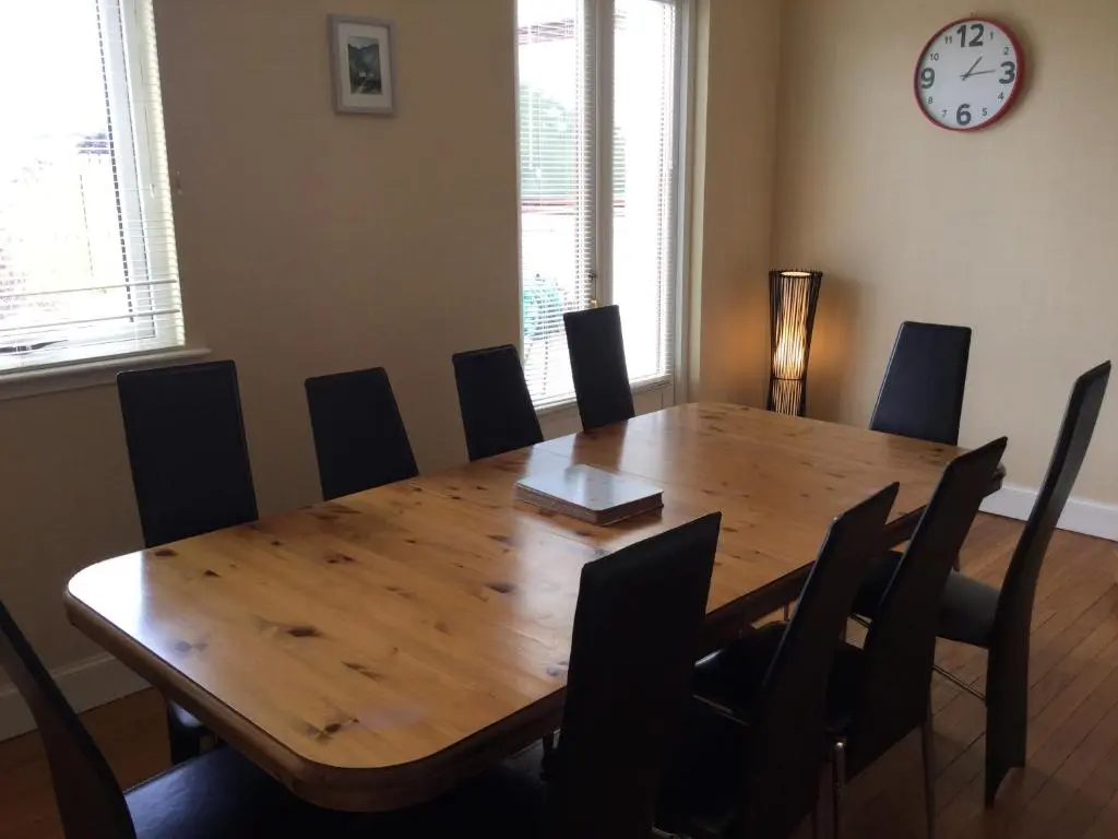 a dining room table with chairs and a clock on the wall at West Heather House Free Parking in Inverness