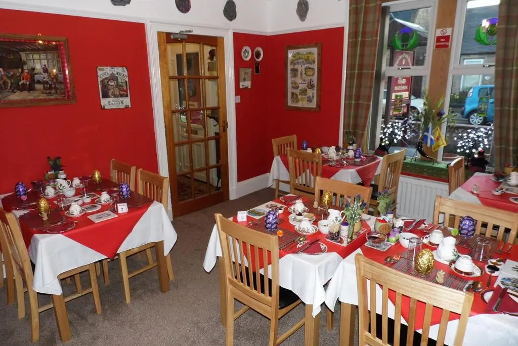 a dining room with red walls and red tables and chairs at Torridon Guest House in Inverness