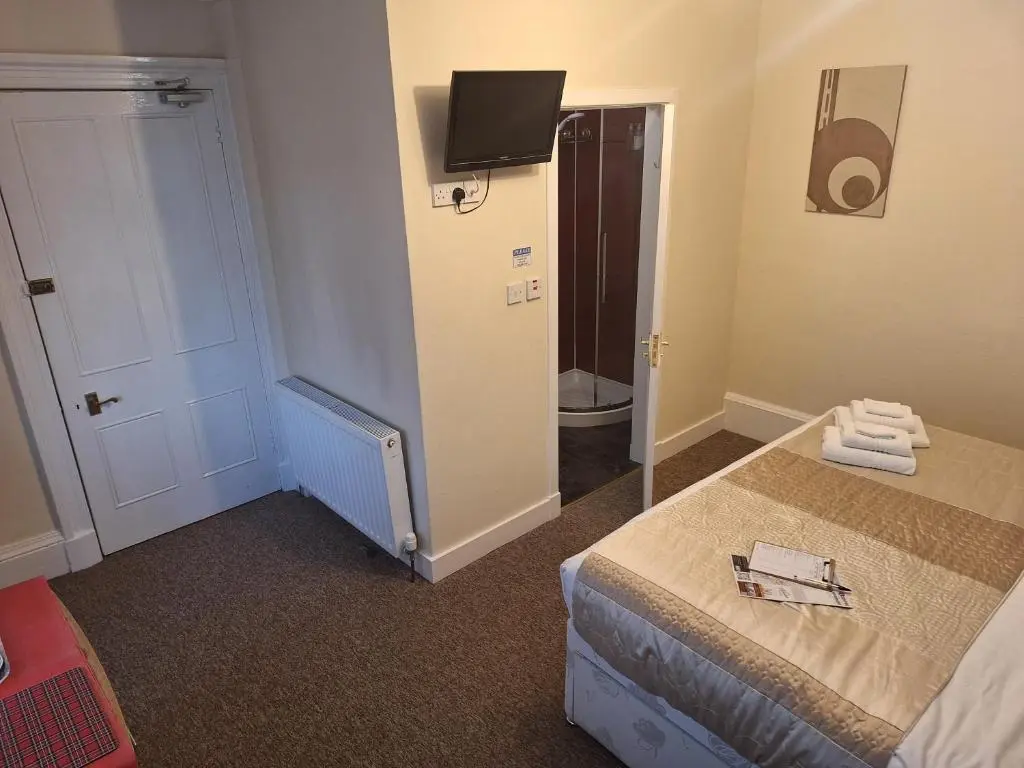 a room with a bed and a bathroom with a mirror at Torridon Guest House in Inverness