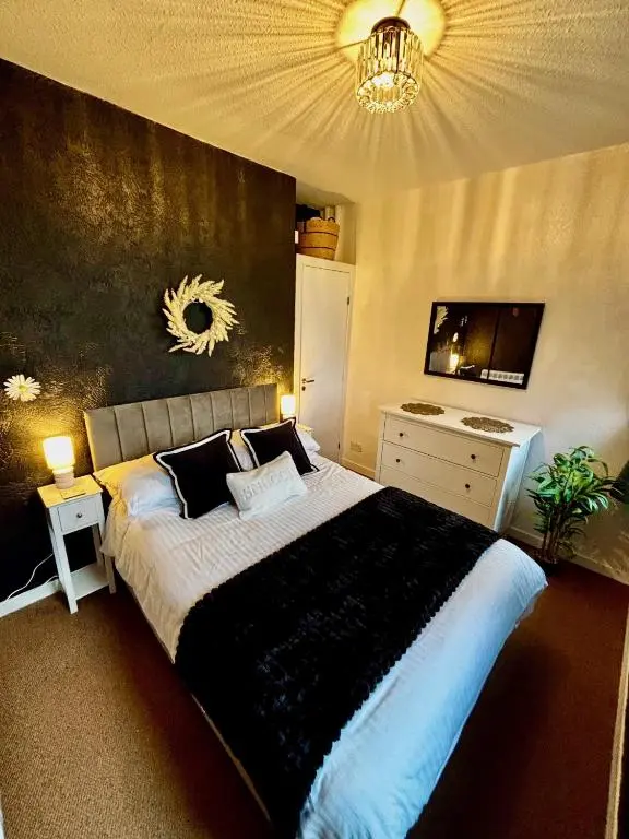 a bedroom with a large bed and a chandelier at Shetland Cottage Kincraig in Kincraig