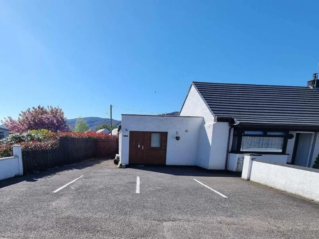 a white house with a garage in a parking lot at Island View Guest House in Ullapool