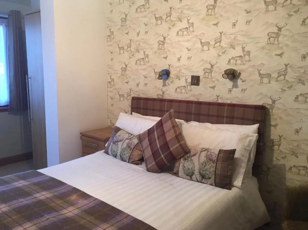 a bedroom with a bed and a wall with deer wallpaper at Island View Guest House in Ullapool