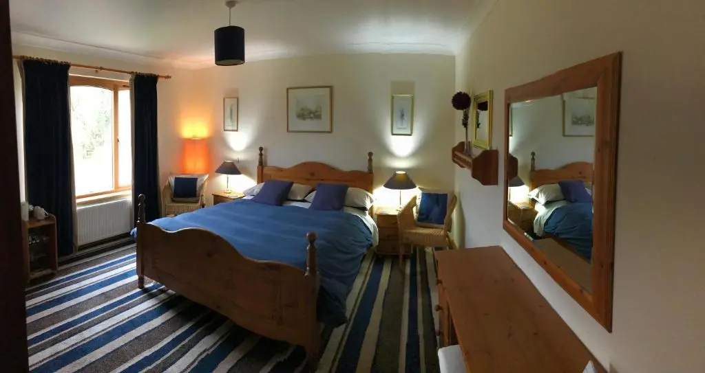 a bedroom with two beds and a mirror at Carn A Chuilinn House in Fort Augustus