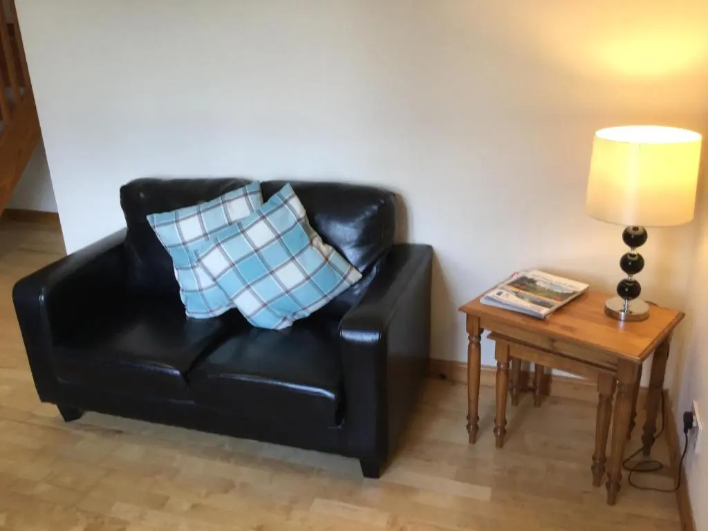 a black leather chair sitting next to a table with a pillow at Culloden Apartment Free Parking in Inverness
