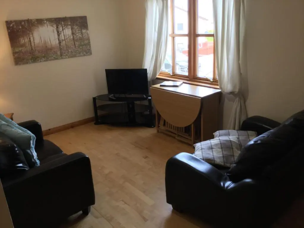 a living room with two black chairs and a desk and a window at Culloden Apartment Free Parking in Inverness
