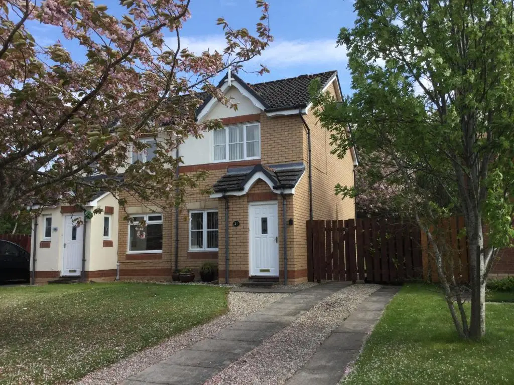 a brick house with a fence and a yard at Castle Heather House Free Parking in Inverness