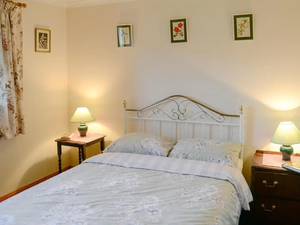 a bedroom with a white bed with two night stands and two lamps at Lower Brae in Achnahanat
